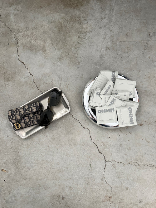 OHHH individual stain remover wipe sachets styled with sunglasses and wallet, on-the-go stain wipes